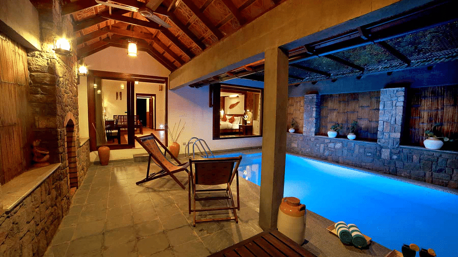 A pool and poolside area with loungers | Vythiri Resort. Wayanad